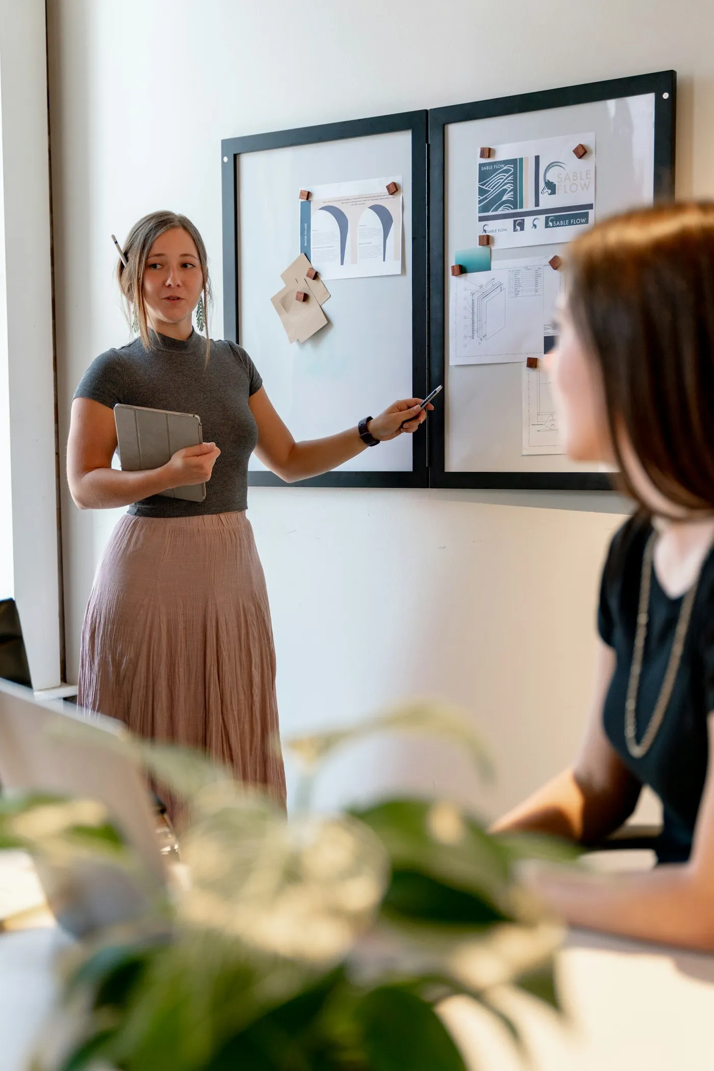 A woman presents ideas on a board to a colleague
